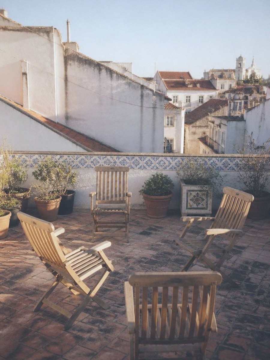 An empty Lisbon rooftop terrace with plants and wooden chairs in a circle